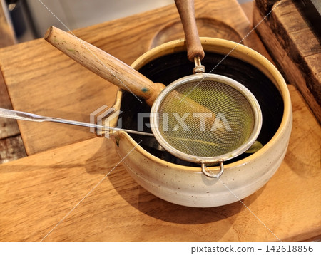 Japanese matcha tea utensils with a sifter and stainless scoop on a ceramic bowl. Japanese matcha tea utensils with a sifter and stainless scoop on a ceramic bowl. 142618856