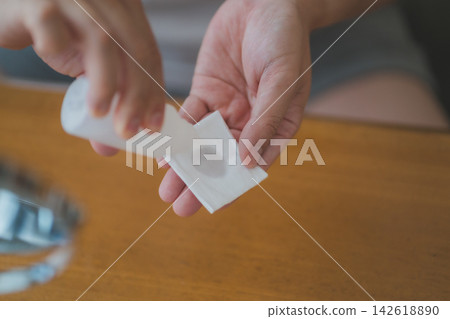 A 40-year-old man's skincare routine: applying lotion to a cotton pad and carefully soaking it in. A 40-year-old man's skincare routine: applying lotion to a cotton pad and carefully soaking it in. 142618890