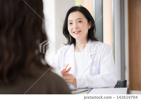 The image of a clinic where a female doctor faces patients and provides medical counseling, examinations, and health consultations with a smile. The image of a clinic where a female doctor faces patients and provides medical counseling, examinations, and health consultations with a smile. 142619704