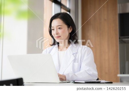 醫療諮詢中的一個場景,一位女醫生正在電腦上將病人資訊和醫療記錄輸入電子病歷系統。 醫療諮詢中的一個場景,一位女醫生正在電腦上將病人資訊和醫療記錄輸入電子病歷系統。 142620255