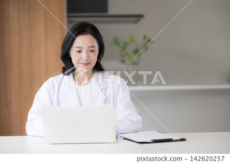 醫療諮詢中的一個場景,一位女醫生正在電腦上將病人資訊和醫療記錄輸入電子病歷系統。 醫療諮詢中的一個場景,一位女醫生正在電腦上將病人資訊和醫療記錄輸入電子病歷系統。 142620257
