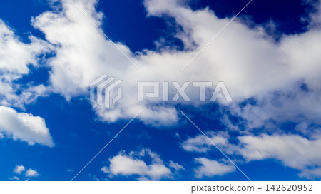 light white clouds scattered across a bright blue sky on a sunny summer day 142620952