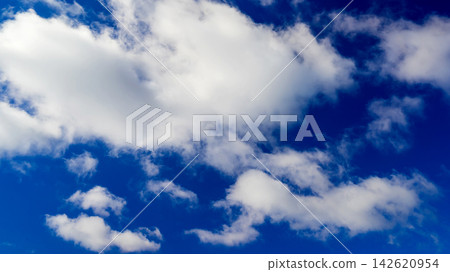 white cumulus clouds of various sizes drifting across a clear blue sky white cumulus clouds of various sizes drifting across a clear blue sky 142620954