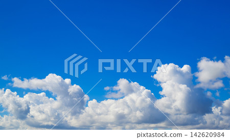 white fluffy clouds line the bottom of a wide clear blue sky 142620984