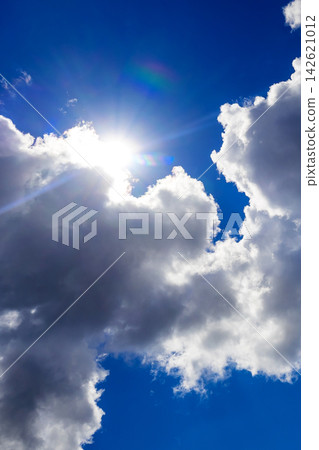 bright sun breaking through fluffy clouds in the deep blue sky bright sun breaking through fluffy clouds in the deep blue sky 142621012