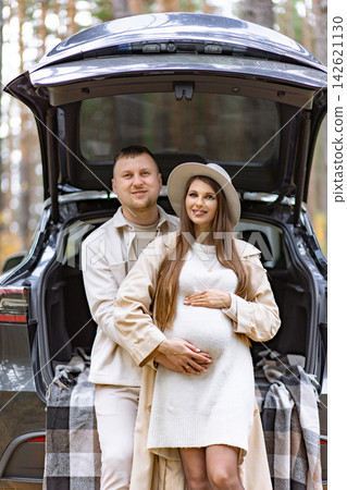 A happy couple expecting a baby poses in front of their car in a natural outdoor setting A happy couple expecting a baby poses in front of their car in a natural outdoor setting 142621130