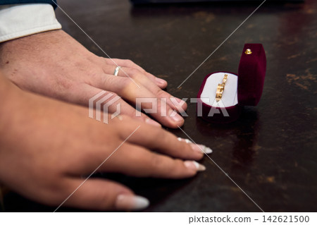View of a couple's hands, placing their wedding rings on their fingers, in a civil ceremony; detail of their rings. Romance, bride and groom, union, love View of a couple's hands, placing their wedding rings on their fingers, in a civil ceremony; detail of their rings. Romance, bride and groom, union, love 142621500