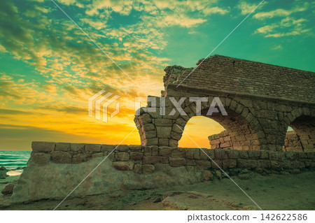 Aqueduct in ancient city Caesarea at sunset. Trendy purple color Aqueduct in ancient city Caesarea at sunset. Trendy purple color 142622586