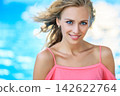 Woman in Coral Pink Top by Blue Background 142622764