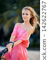 Woman in Pink Dress Outdoors 142622767