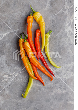 Colorful Long Chili Peppers On Marble Background For Cooking And Culinary Inspiration Colorful Long Chili Peppers On Marble Background For Cooking And Culinary Inspiration 142622835