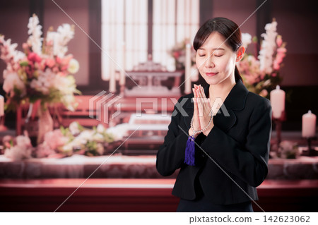 葬禮上,一位女子戴著念珠,雙手合十。 葬禮上,一位女子戴著念珠,雙手合十。 142623062