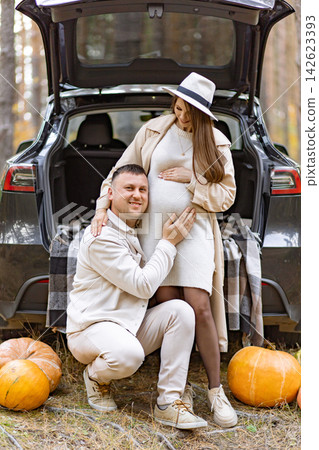 A happy couple poses in a forest setting, celebrating their pregnancy and the fall season A happy couple poses in a forest setting, celebrating their pregnancy and the fall season 142623393
