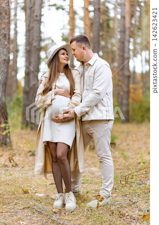 A loving couple embraces in a forest, celebrating their upcoming parenthood with affection and joy A loving couple embraces in a forest, celebrating their upcoming parenthood with affection and joy 142623421