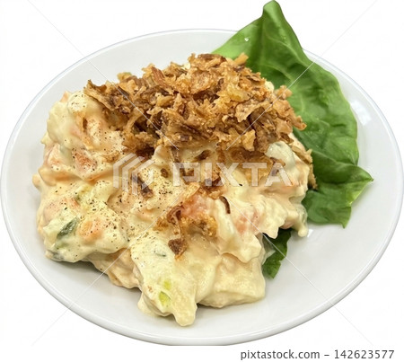 A mouthwatering overhead photograph of potato salad served on a white round plate against a white background, garnished with fried onions and shiso leaves. 142623577