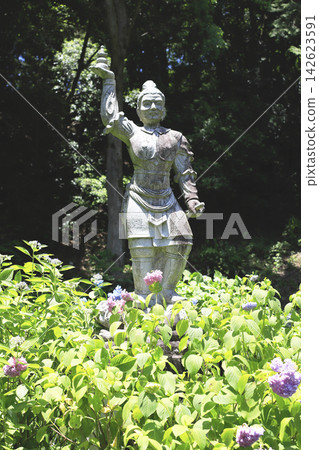 A stone statue of Tamonten (Bishamonten) amidst the greenery, holding a treasure pagoda high in his right hand. A stone statue of Tamonten (Bishamonten) amidst the greenery, holding a treasure pagoda high in his right hand. 142623591