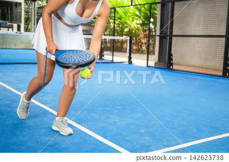 Athlete ready to serve padel ball on vibrant blue court Athlete ready to serve padel ball on vibrant blue court 142623738