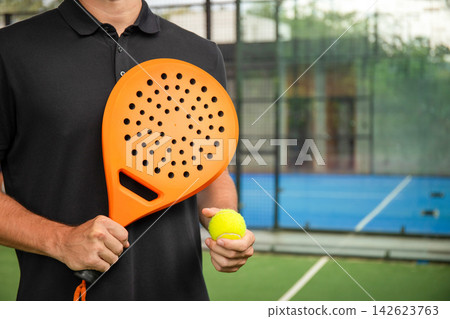 Padel player on court with orange paddle and yellow ball Padel player on court with orange paddle and yellow ball 142623763