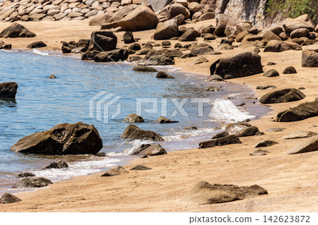 A coastal landscape featuring a sandy beach with rocky areas and crashing waves. A coastal landscape featuring a sandy beach with rocky areas and crashing waves. 142623872