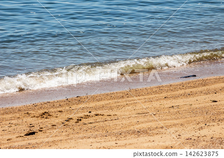 夏日海灘水邊的波浪和美麗的沙紋。 夏日海灘水邊的波浪和美麗的沙紋。 142623875