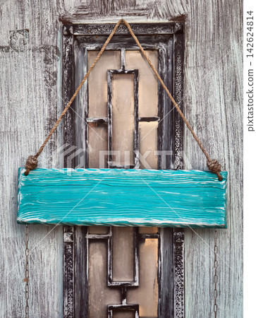 A custom wooden sign hanging on a door with a decorative window design in an urban setting. A custom wooden sign hanging on a door with a decorative window design in an urban setting. 142624814