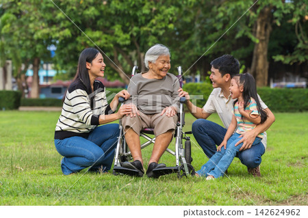 cheerful family taking care of elderly grandmother in wheelchair outdoors at park cheerful family taking care of elderly grandmother in wheelchair outdoors at park 142624962