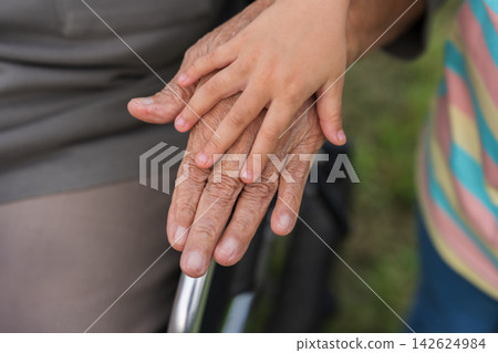 close up of senior and child holding hands on wheelchair armrest close up of senior and child holding hands on wheelchair armrest 142624984