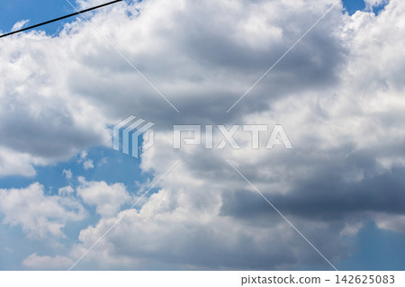A view of the silhouette of power lines crossing the upper left and thick, layered clouds spreading across the sky - from a low-angle perspective. A view of the silhouette of power lines crossing the upper left and thick, layered clouds spreading across the sky - from a low-angle perspective. 142625083