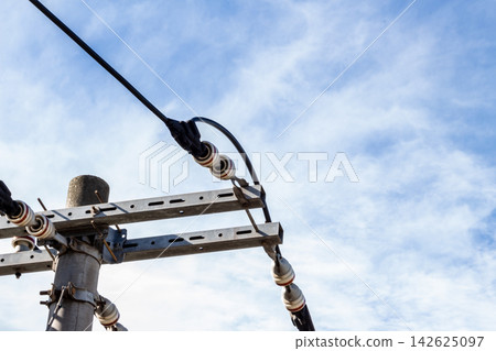 Close-up of the crossarms and insulators on a utility pole, and the wiring structure being routed through them - from a low-angle shot. Close-up of the crossarms and insulators on a utility pole, and the wiring structure being routed through them - from a low-angle shot. 142625097
