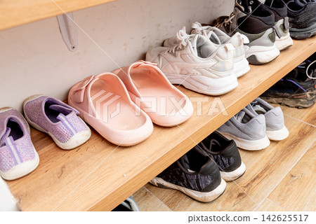 Storing keeping footwear in the hallway, pairs of different shoes on shelf Storing keeping footwear in the hallway, pairs of different shoes on shelf 142625517