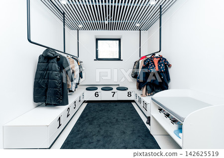 Autumn outerwear jacket and coat on hangers in wooden wardrobe shelf in hallway 142625519