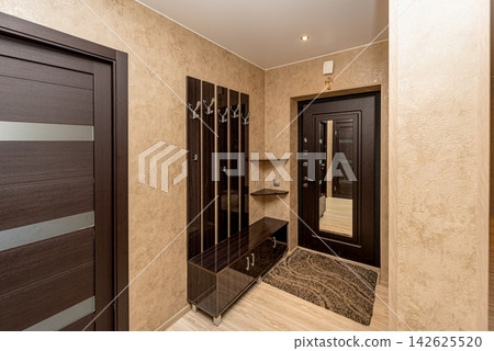 Hallway in residential apartment flat with organized shoe shelves and coat hooks Hallway in residential apartment flat with organized shoe shelves and coat hooks 142625520