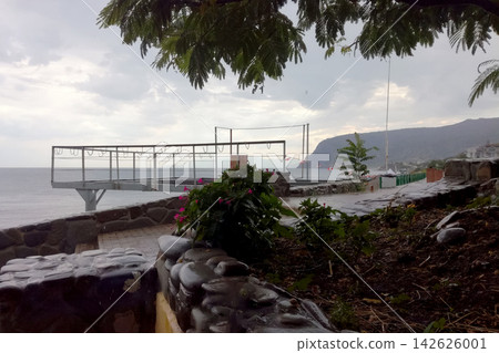 stone parapet and metal pier on sea coast near mountains 142626001
