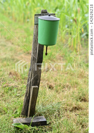 Rural washbasin hangs on wooden post near grassy area with simple outdoor design. 142626218