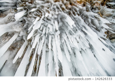 Ice icicles hanging on stone surface of cave, frozen water lake Baikal in winter 142626333