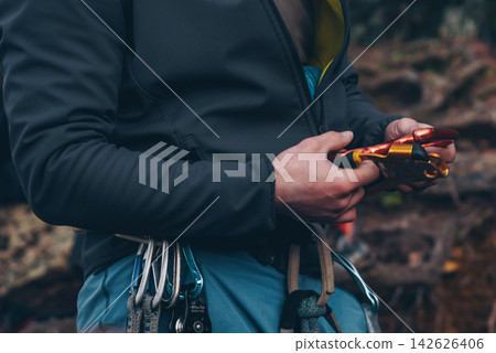 Rock climber tying knot on rope for climber, man preparing climbing equipment Rock climber tying knot on rope for climber, man preparing climbing equipment 142626406