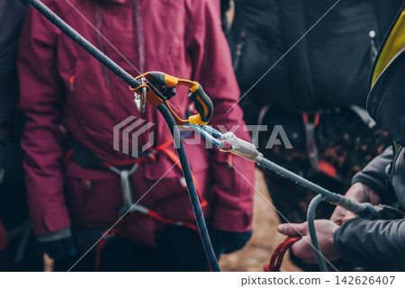 Rock climber tying knot on rope for climber, man preparing climbing equipment Rock climber tying knot on rope for climber, man preparing climbing equipment 142626407