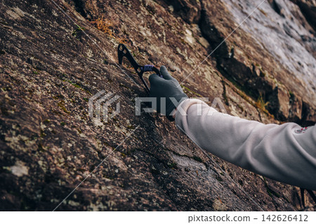 Rock climber climbing high rock wall, extreme sport outside, alpinism equipment Rock climber climbing high rock wall, extreme sport outside, alpinism equipment 142626412