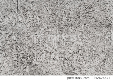Weathered concrete wall demonstrates rough plaster texture with embossed patterns. 142626677