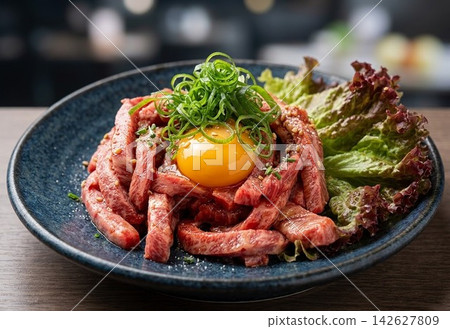 Wagyu Yukhoe: Vibrant raw meat and egg yolk served on a black plate (Menu item at izakaya/yakiniku restaurant, gourmet ingredient) Wagyu Yukhoe: Vibrant raw meat and egg yolk served on a black plate (Menu item at izakaya/yakiniku restaurant, gourmet ingredient) 142627809