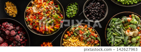 A selection of frozen fruits and vegetables neatly arranged in plates, with a dark background, highlighting the practice of preserving summer produce for winter, banner A selection of frozen fruits and vegetables neatly arranged in plates, with a dark background, highlighting the practice of preserving summer produce for winter, banner 142627963
