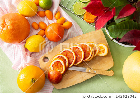 Citrus fruits are being prepared for Christmas drying. Different types of citrus are placed on a cutting board and drying rack in a home kitchen. The scene shows a festive activity Citrus fruits are being prepared for Christmas drying. Different types of citrus are placed on a cutting board and drying rack in a home kitchen. The scene shows a festive activity 142628042