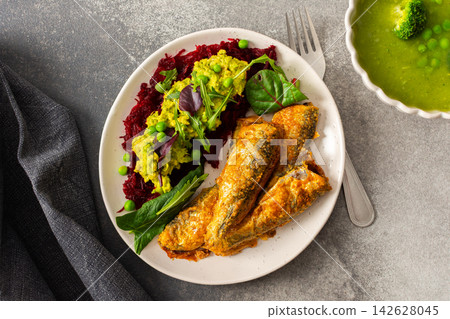 Baked small sea fish is served alongside boiled beets, hummus, green peas, and herbs. This dish is suitable for breakfast and offers a healthy option Baked small sea fish is served alongside boiled beets, hummus, green peas, and herbs. This dish is suitable for breakfast and offers a healthy option 142628045