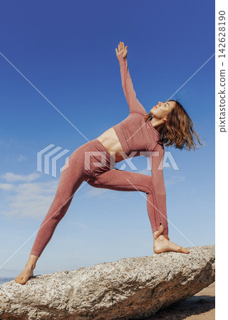 Woman doing yoga on sandy beach, female sport background sea blue sky, sunny day Woman doing yoga on sandy beach, female sport background sea blue sky, sunny day 142628190