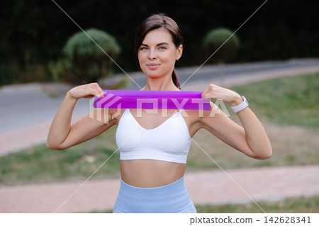 Fitness model exercising with resistance band in a park 142628341