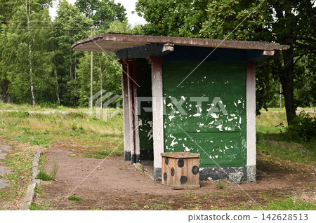 Old green bus stop standing on roadside near forest on summer day. Old green bus stop standing on roadside near forest on summer day. 142628513