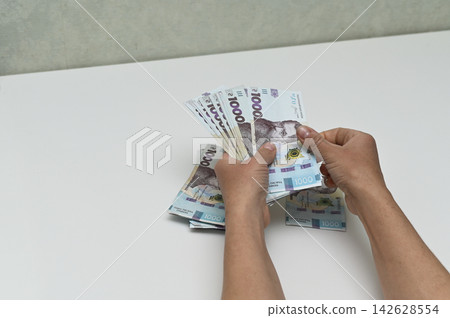 money counted in hands over white table, money counted in hands over white table, 142628554