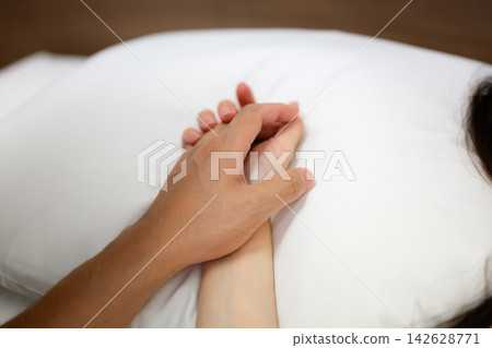 A man and a woman holding hands in bed A man and a woman holding hands in bed 142628771