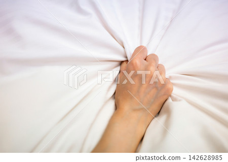 床上,一個女人緊緊抓著床單。 床上,一個女人緊緊抓著床單。 142628985