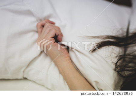 床上，一個女人緊緊抓著床單。 142628986